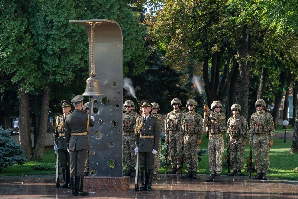 Дзвін памʼяті на меморіалі біля Міністерства оборони України: сталева плита, пробита уламками, почесна варта і залповий салют. Київ, 2019 рік.